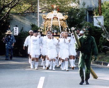 西の地岡崎神社の祭りで神輿を担いで歩く人々の写真