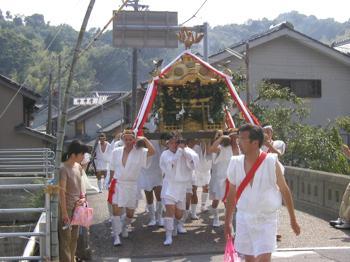 木岐八幡神社の祭りで神輿を担いで歩く人々の写真