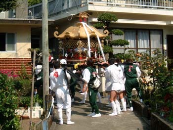志和岐吉野神社祭で神輿を担いで民家付近を歩く人々の写真