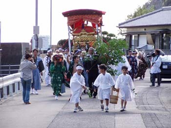 伊座利新田八幡神社祭で神輿を担いで歩く人々の写真